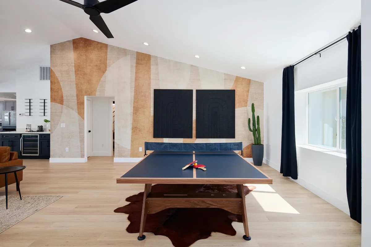 A vibrant and playful recreation area with a ping pong table, colorful abstract wall art, and a cactus plant. The space is full of energy, ideal for group activities and casual competitions.