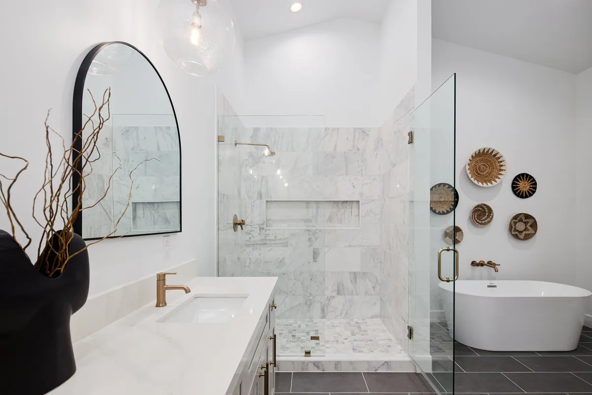 A luxurious bathroom featuring a freestanding bathtub, a spacious shower area, and a vanity with a mirror. The design is sleek and calming, evoking a spa-inspired atmosphere.
