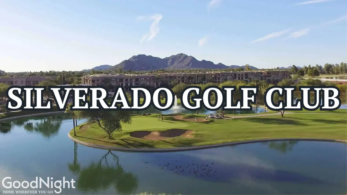 A lush golf course stretches out under the Arizona sky, with a tranquil lake reflecting the sun and majestic mountains in the background. Resort buildings dot the edge of the course, while a few golfers enjoy a quiet round surrounded by manicured greens and serene water features.