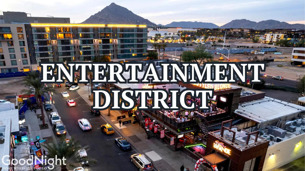 The photo captures Scottsdale's bustling Entertainment District at night, featuring energetic signage, cars cruising busy streets, and rooftop dining areas filled with people enjoying the lively nightlife.